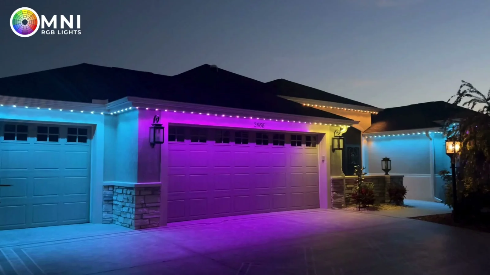 Home at dusk with permanent RGB lights under the roofline washing the garage in blue and purple