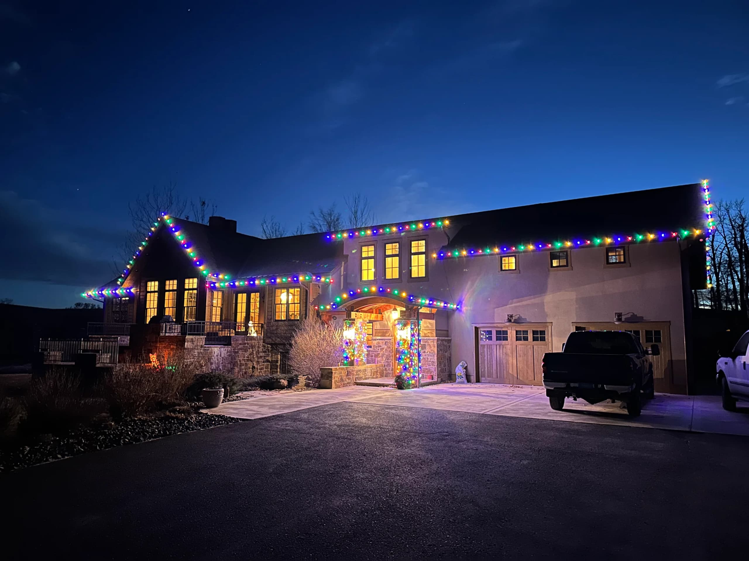 Large home with multicolor roofline lights at dusk