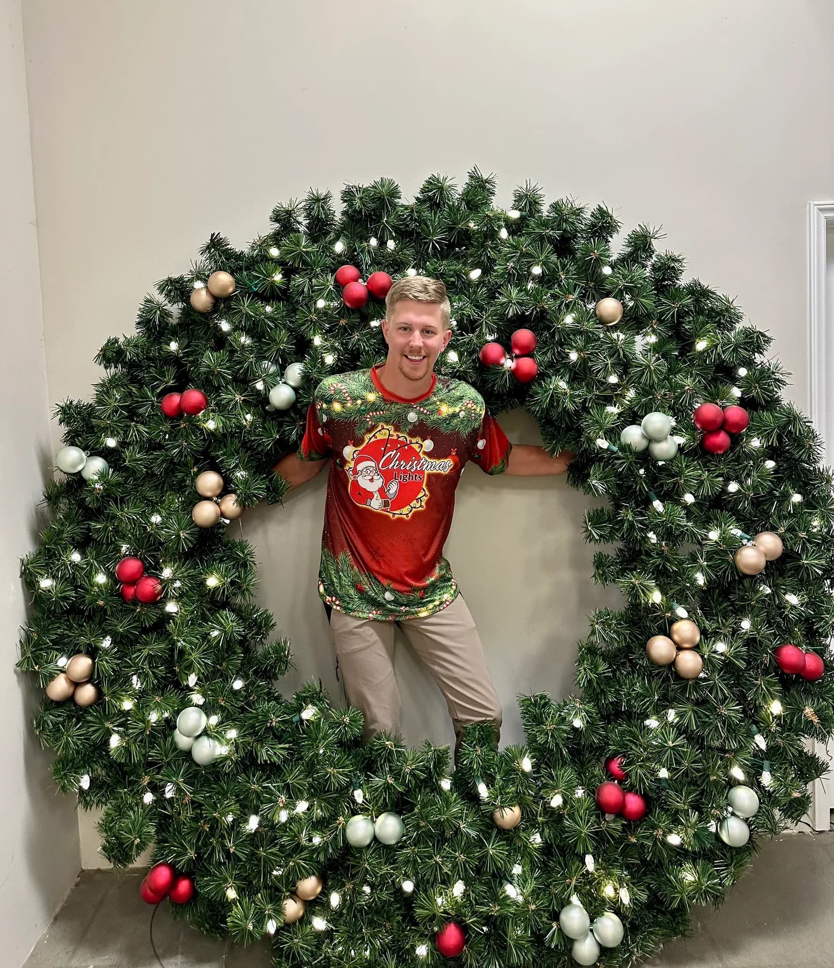 Installer standing inside an oversized decorated wreath before it is hung