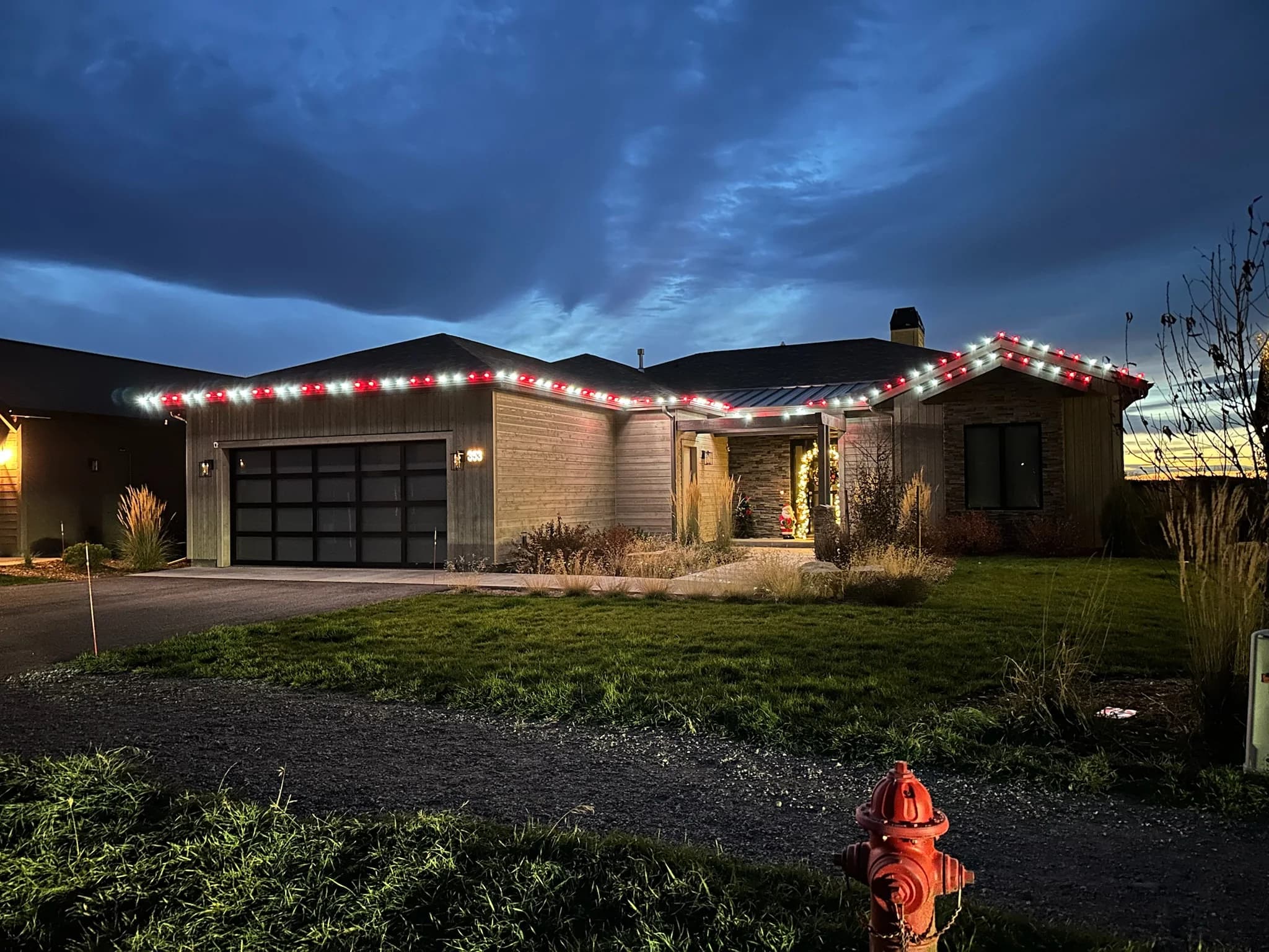 Single-story home with red and white roofline lights at dusk under a blue sky