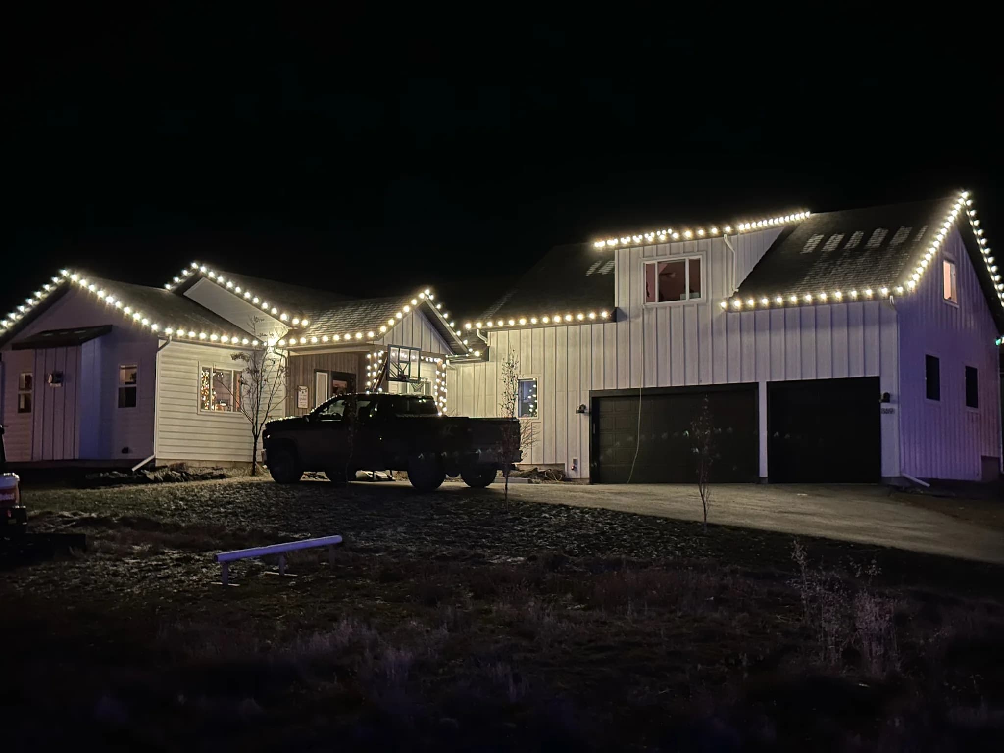 Modern farmhouse with a three-car garage outlined in bright white roofline lights